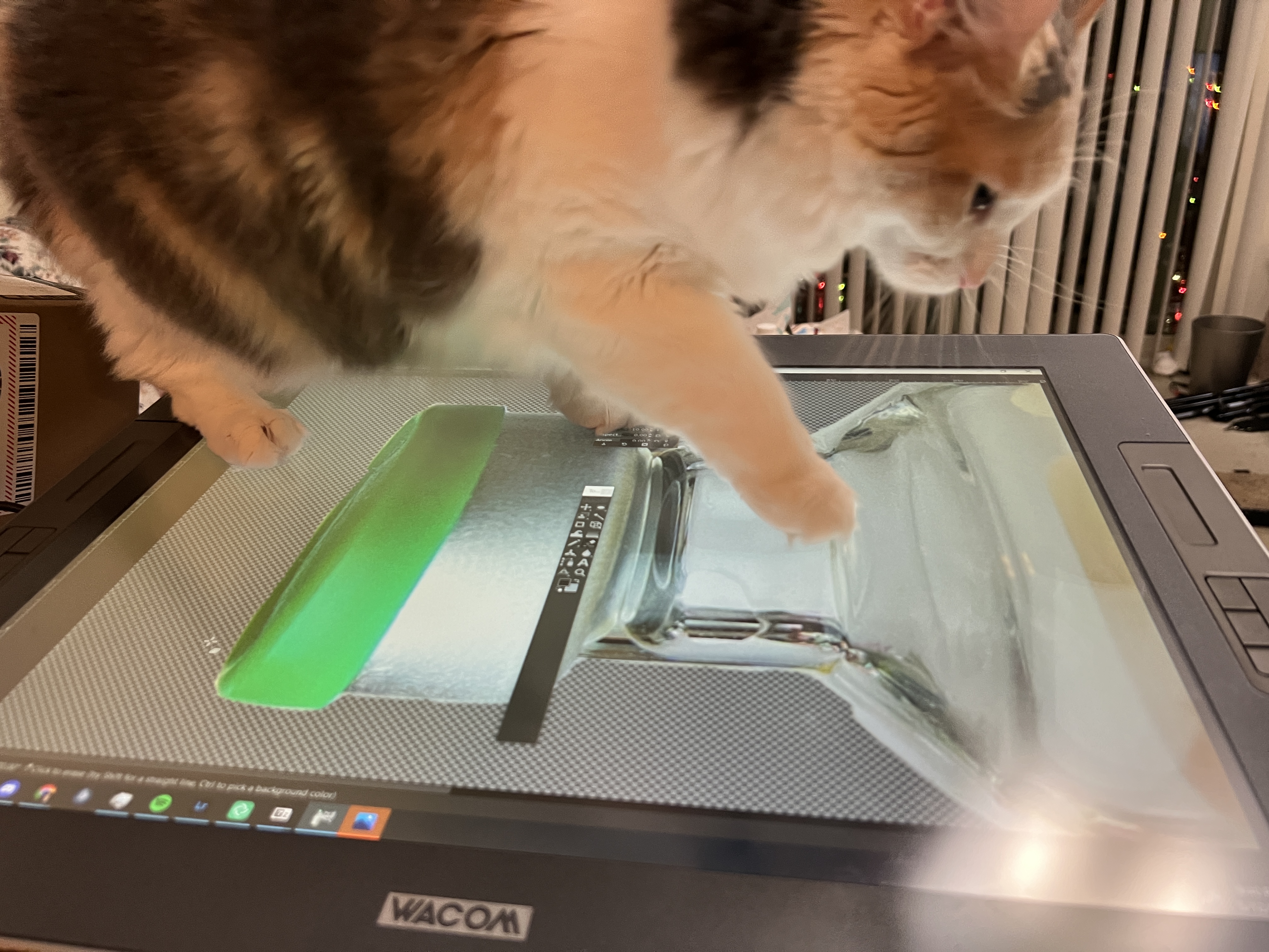 A photo of a cat walking on a Wacom graphics tablet with the top of a vial on the screen